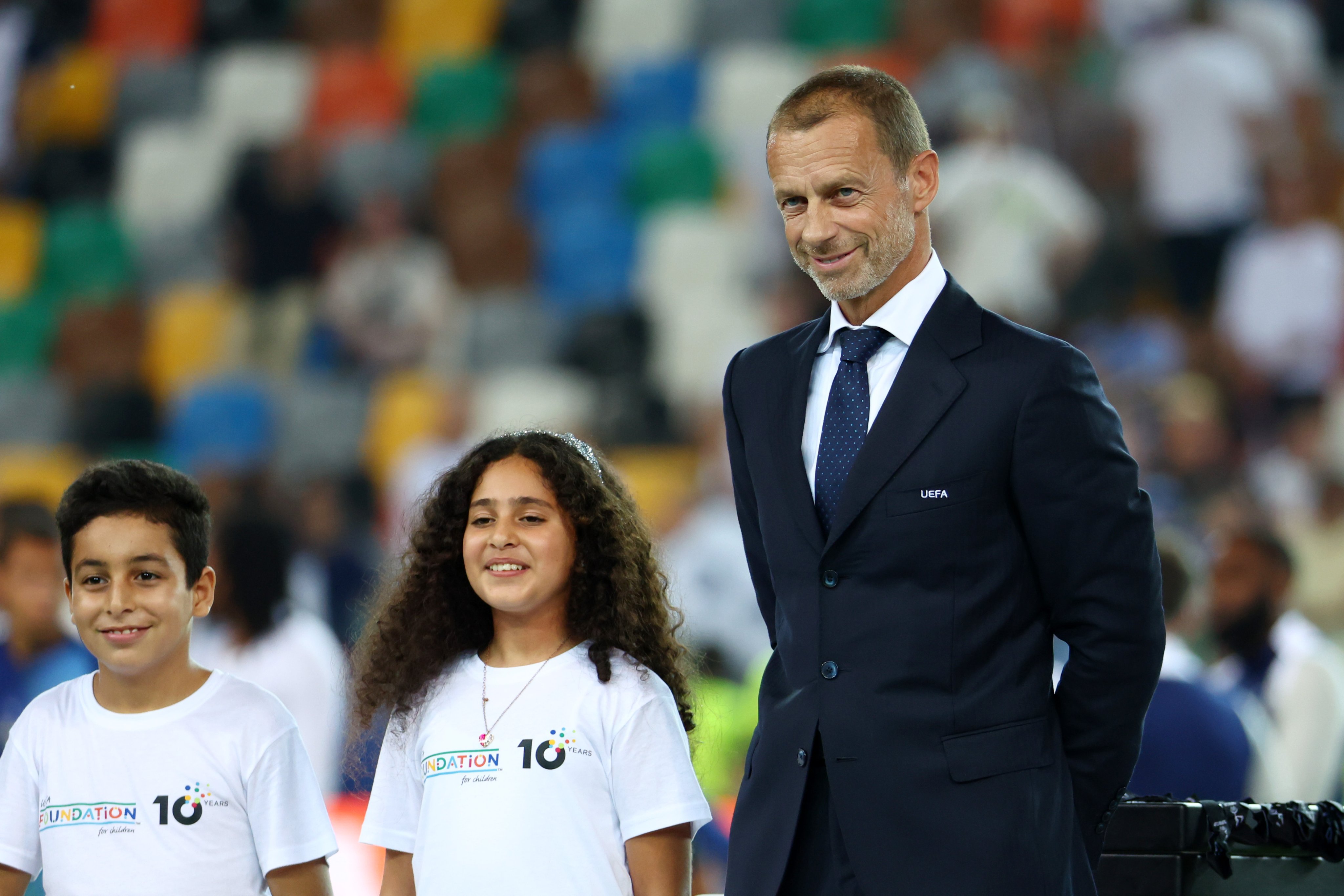 طفلان من غزة جانب رئيس الاتحاد الأوروبي لكرة القدم، في كأس السوبر الأوروبي 2025